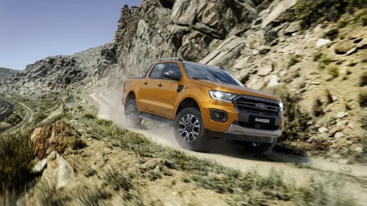 Ford Ranger Wildtrak màu vàng đang chạy trên địa hình đất