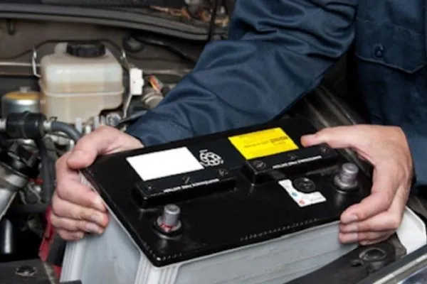 Thợ máy đang kiểm tra hệ thống dây điện và vị trí lắp đặt ắc quy ô tô trong khoang động cơ