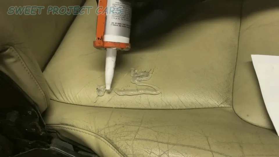 Cảnh quay cận cảnh thao tác cán phẳng lớp keo silicone lên vết nứt trên ghế da ô tô