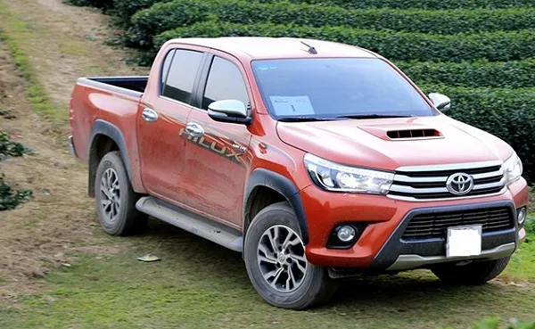 Xe Toyota Hilux màu trắng đang đậu trên đường, minh họa cho dịch vụ cho thuê xe bán tải có lái