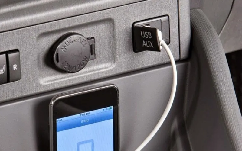 Một người dùng đang cắm cáp USB để kết nối điện thoại với màn hình ô tô
