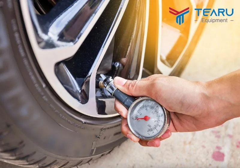 Đồng hồ đo áp suất lốp xe hơi và người đang thực hiện cách đọc thông số áp suất lốp ô tô