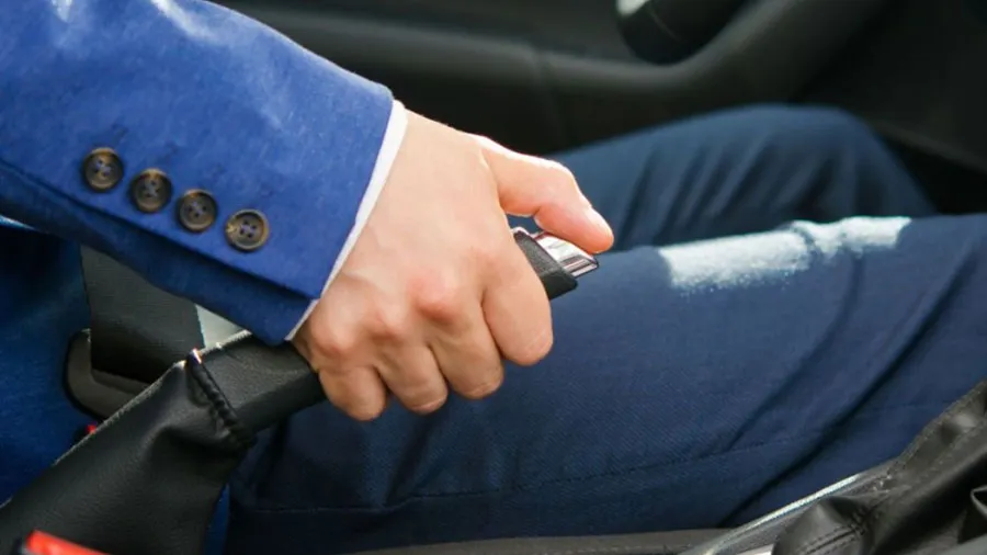 Hình ảnh người lái xe thao tác nhả phanh tay bằng cách kéo nhẹ cần và ấn nút khóa