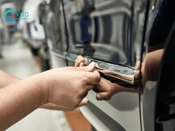 Hình ảnh minh họa một người đang dùng khăn sạch và dung dịch tẩy rửa chuyên dụng để lau sạch bề mặt kính đã tẩy keo