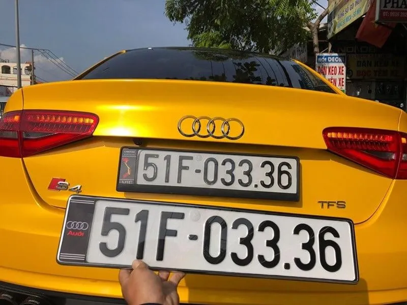 Người thợ đang sử dụng tua vít để tháo biển số xe ô tô bị rỉ sét