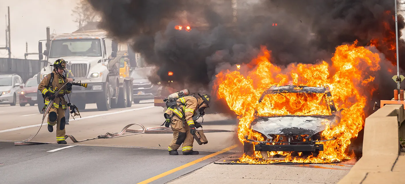 Mô tả hình ảnh: Hai người giám định đang kiểm tra và ghi chép chi tiết về một chiếc xe ô tô bị hư hỏng nặng sau tai nạn
