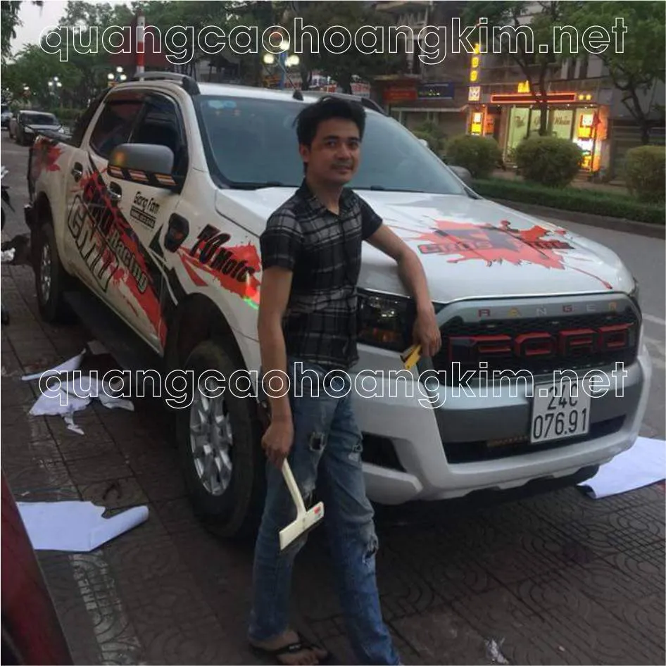 Hình ảnh minh họa thợ đang sử dụng phương pháp dán ướt để dán tem phức tạp lên xe bán tải, cho thấy khả năng điều chỉnh vị trí linh hoạt trước khi keo khô