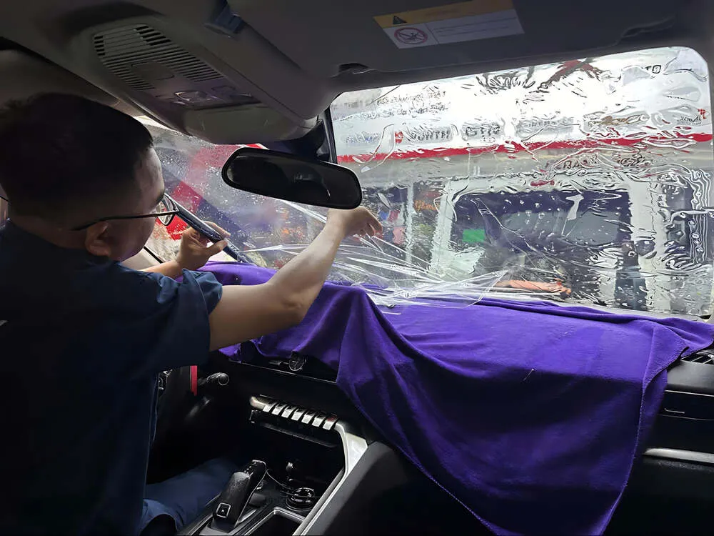 Một kỹ thuật viên chuyên nghiệp đang hoàn thành công đoạn dán phim cách nhiệt trên kính xe