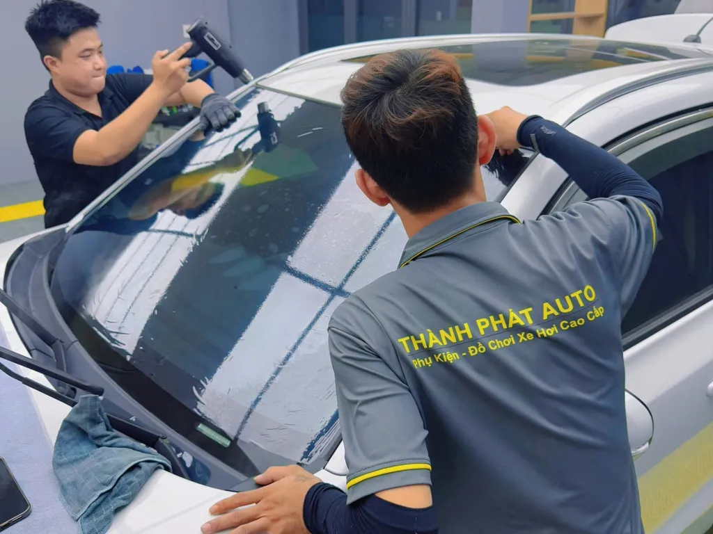 Kỹ thuật viên đang dán phim cách nhiệt 3M cho kính lái ô tô trong môi trường tiêu chuẩn