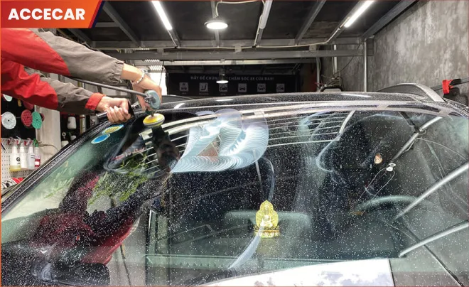 Thợ kỹ thuật đang đánh bóng kính chắn gió ô tô tại gara chuyên nghiệp