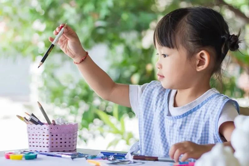 Bé gái đang tô màu cho bức vẽ ô tô đã hoàn thành