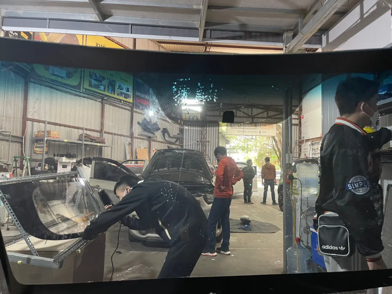 Học viên đang thực hành dán phim cách nhiệt trên mô hình và xe thực tế tại xưởng đào tạo