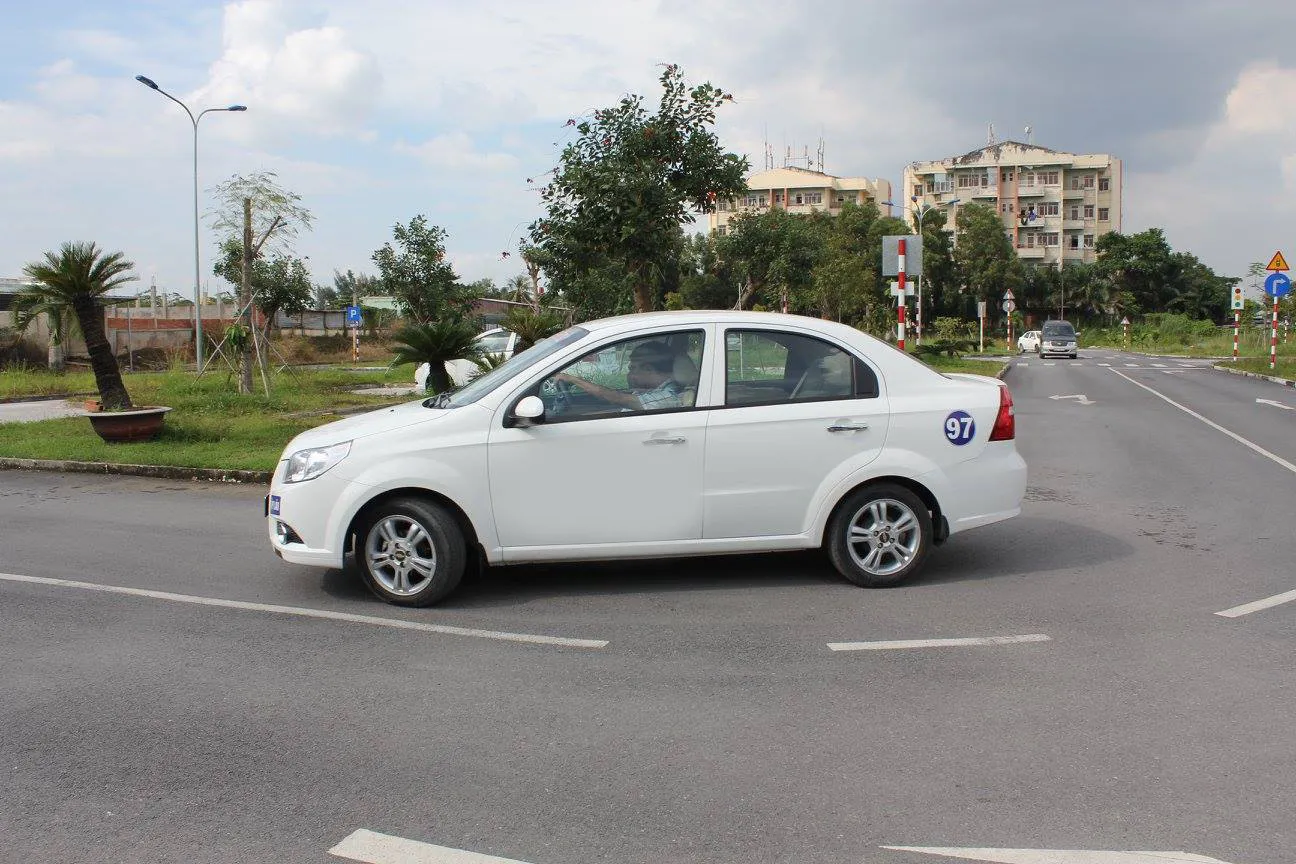 Giáo viên đang hướng dẫn học viên thực hành lái xe trên đường trường