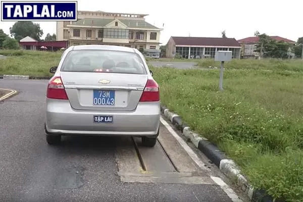 Thí sinh tập luyện bài thi lái xe qua đường hẹp vuông góc và vệt bánh xe trên sân sa hình