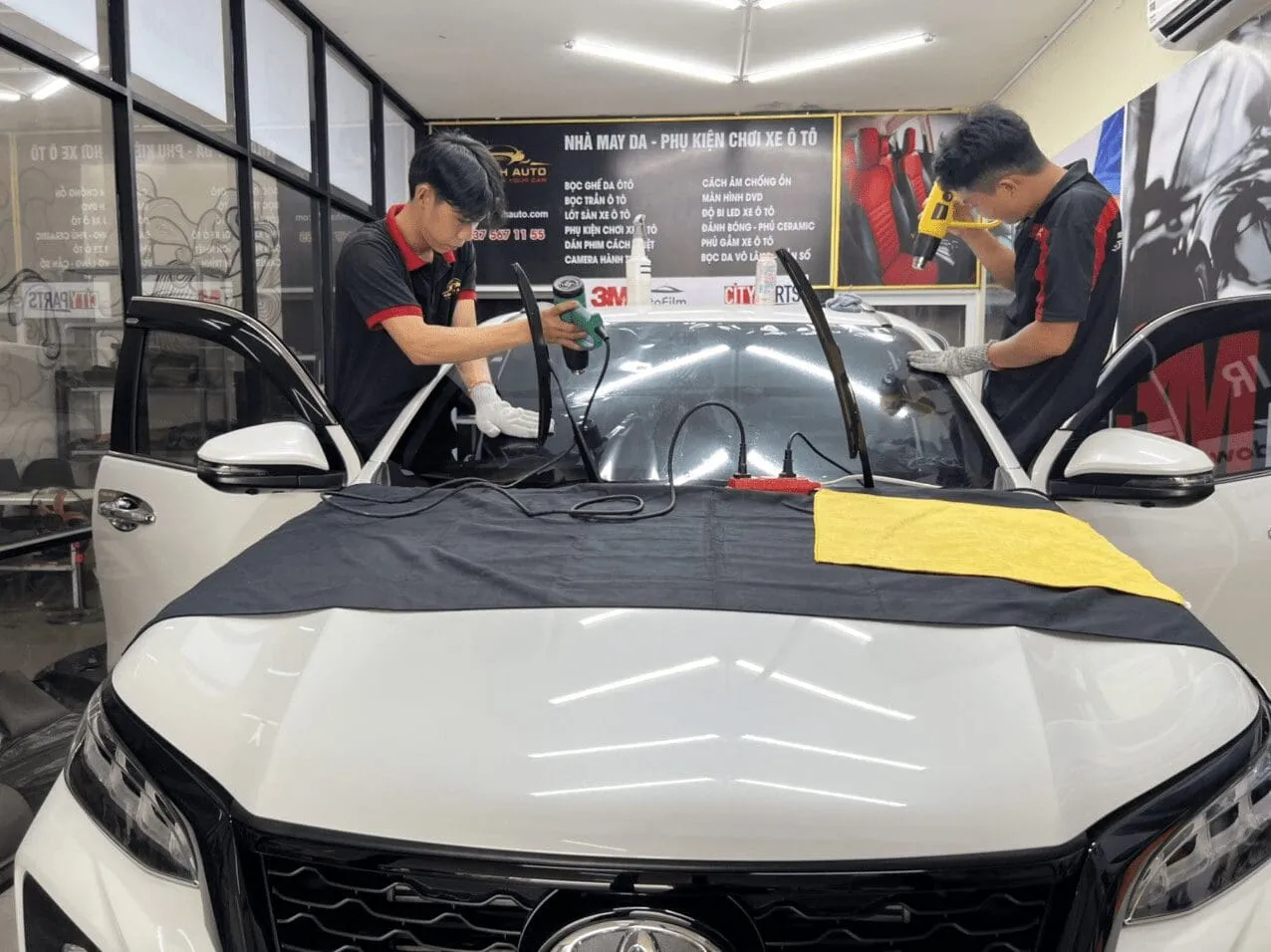Kỹ thuật viên đang kiểm tra và chuẩn bị bề mặt kính xe hơi trước khi dán film cách nhiệt ô tô 3M