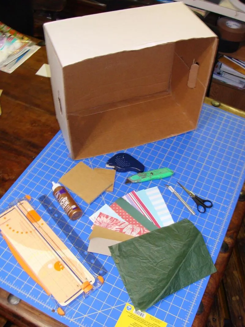 Chuẩn bị đầy đủ dụng cụ làm ô tô bằng bìa carton, bao gồm hộp giấy, kéo, keo dán và vật liệu trang trí