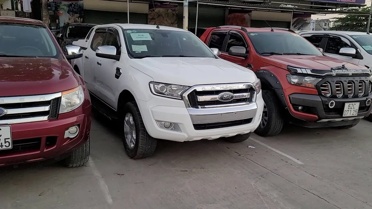 Một người thợ đang kiểm tra kỹ lưỡng phần động cơ và các chi tiết cơ khí của một chiếc xe bán tải cũ