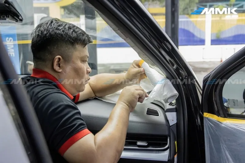 Cận cảnh một kỹ thuật viên đang dán phim cách nhiệt VKOOL lên cửa kính ô tô trong phòng dán chuyên dụng