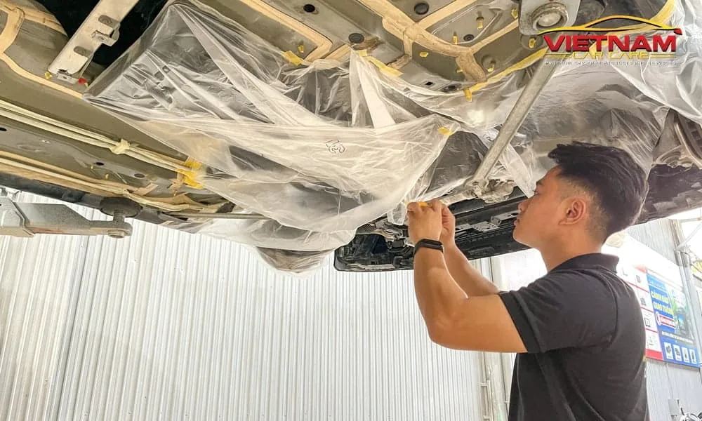 Kỹ thuật viên thực hiện bao bọc gầm xe kỹ lưỡng trước khi sơn phủ gầm.