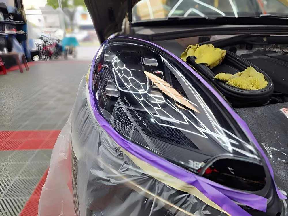 Kỹ thuật viên đang sử dụng máy sấy chuyên dụng để loại bỏ hơi nước khỏi đèn pha