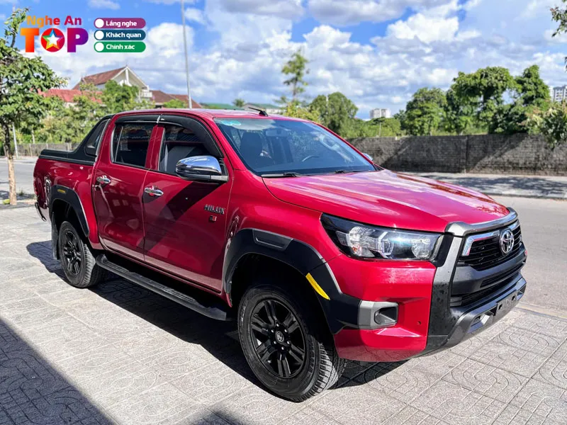 Khách hàng đang kiểm tra chi tiết một chiếc xe bán tải cũ dưới sự hỗ trợ của nhân viên showroom