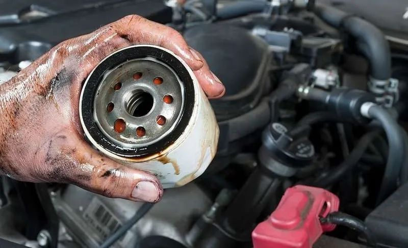 Thao tác tháo lọc nhớt cũ trên động cơ xe tải