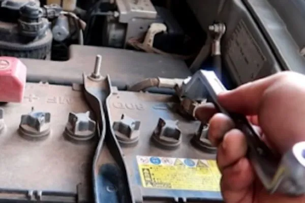 Quy trình tháo ắc quy xe ô tô cũ đang được thực hiện, dây cáp cực âm đã được tháo rời an toàn