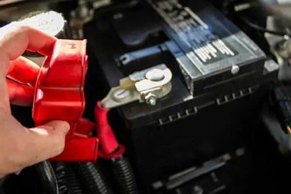 Cáp điện cực dương màu đỏ đang được nối chắc chắn vào đầu cực dương của ắc quy xe ô tô mới