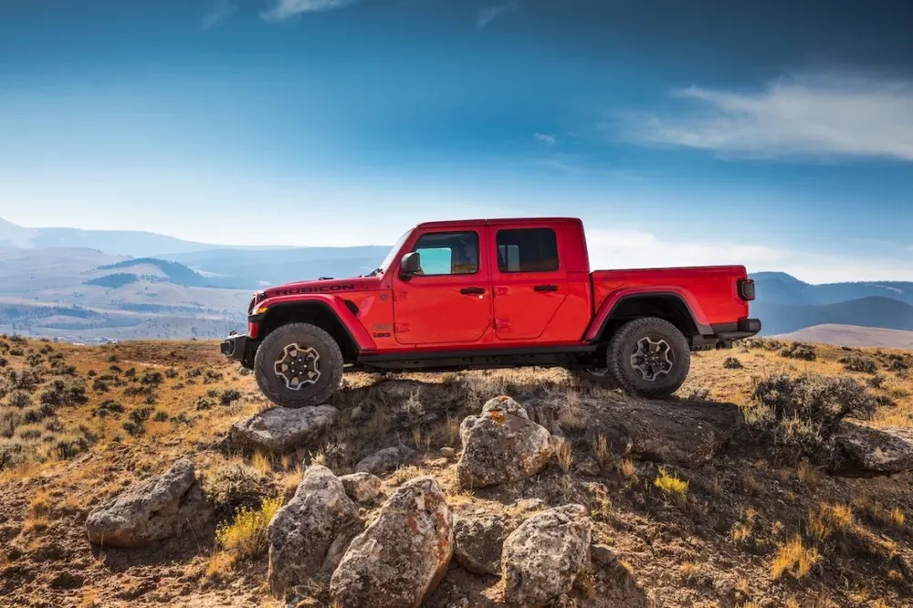 Jeep Gladiator 2023 màu xanh quân đội đang vượt qua địa hình đá khó khăn, thể hiện khả năng off-road vượt trội