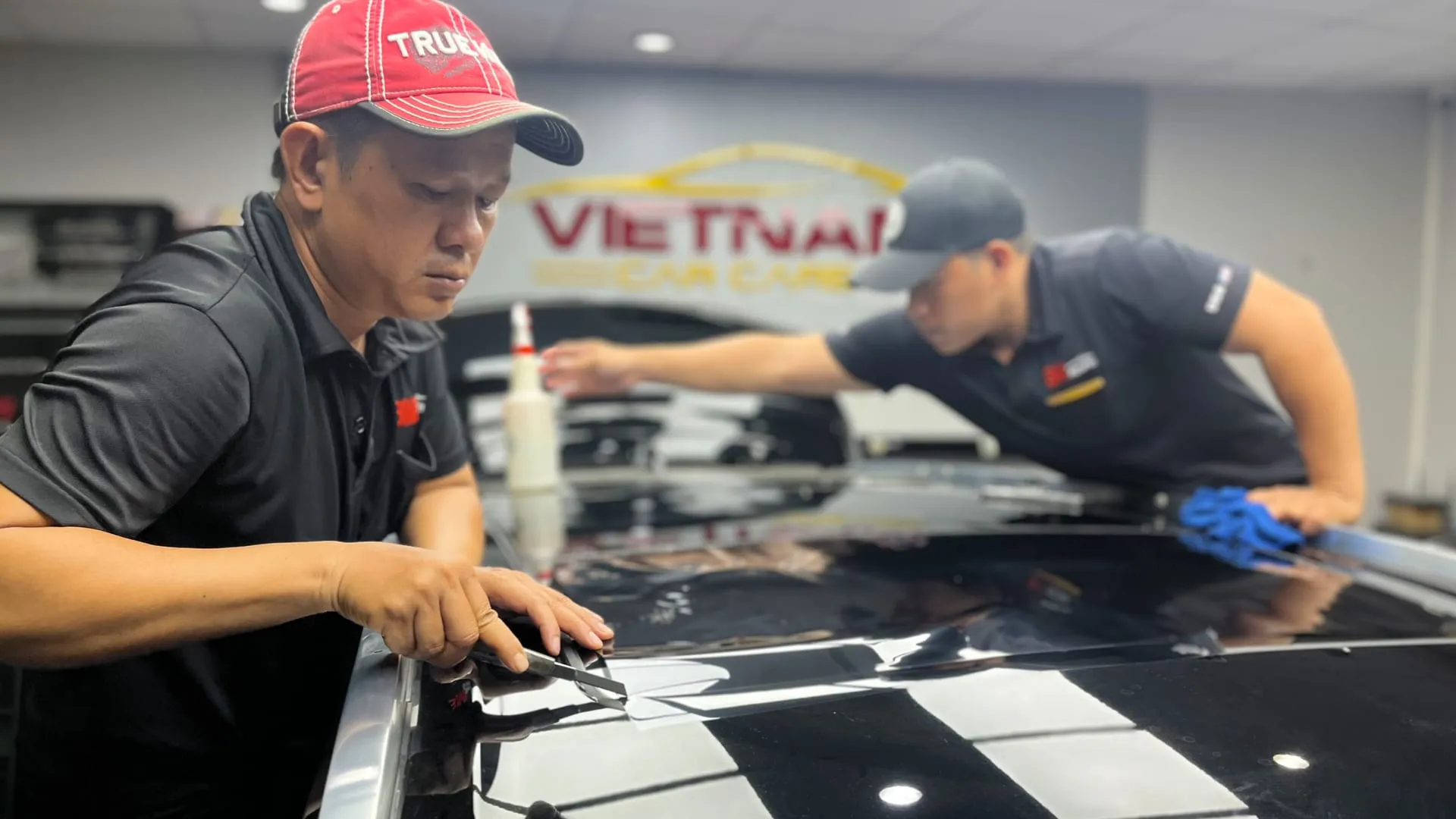 Kỹ thuật viên đang thi công dán phim cách nhiệt 3M cho kính lái, một quy trình đòi hỏi sự tỉ mỉ, độ chính xác cao và kinh nghiệm dày dặn