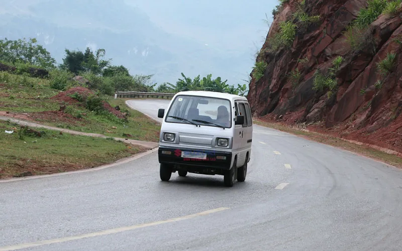 Suzuki Blind Van màu trắng đang di chuyển trên đường phố đô thị, thể hiện tính linh hoạt và khả năng chở hàng của allintitle:xe bán tải su cóc