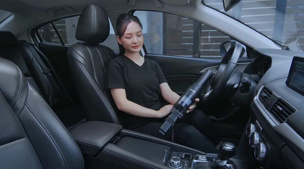 Bên trong xe ô tô đang được vệ sinh bằng máy hút bụi cầm tay và dụng cụ chuyên nghiệp