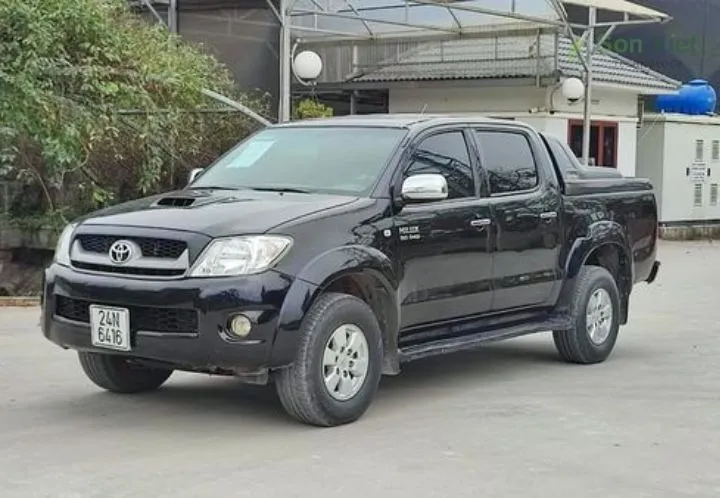 Xe bán tải Toyota Hilux màu đen đang chạy trên đường đất, thể hiện khả năng chịu đựng