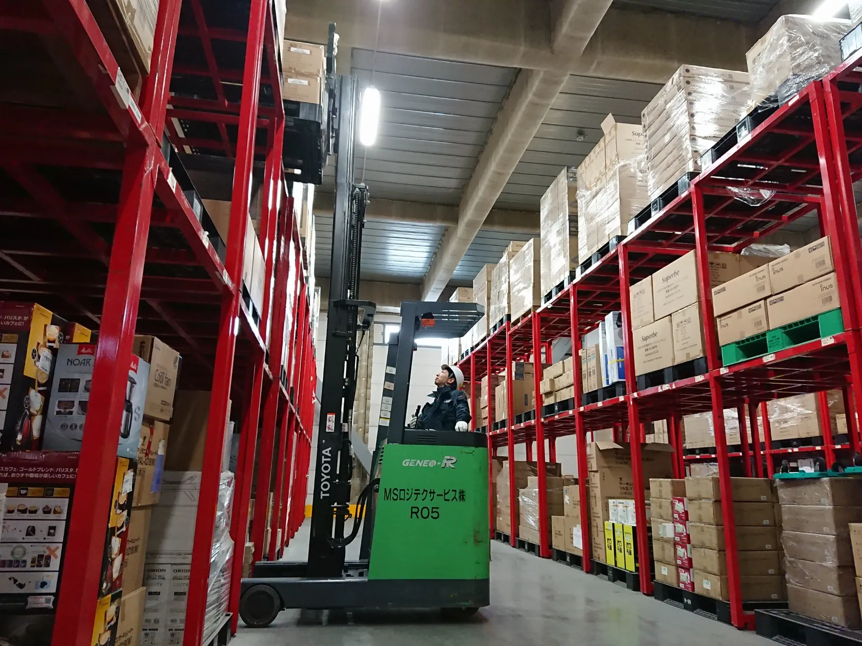 Xe nÃ¢ng Ä'iá»‡n Ä'á»©ng lÃ¡i Ä'ang lÃ m viá»‡c trong kho hÃ ng