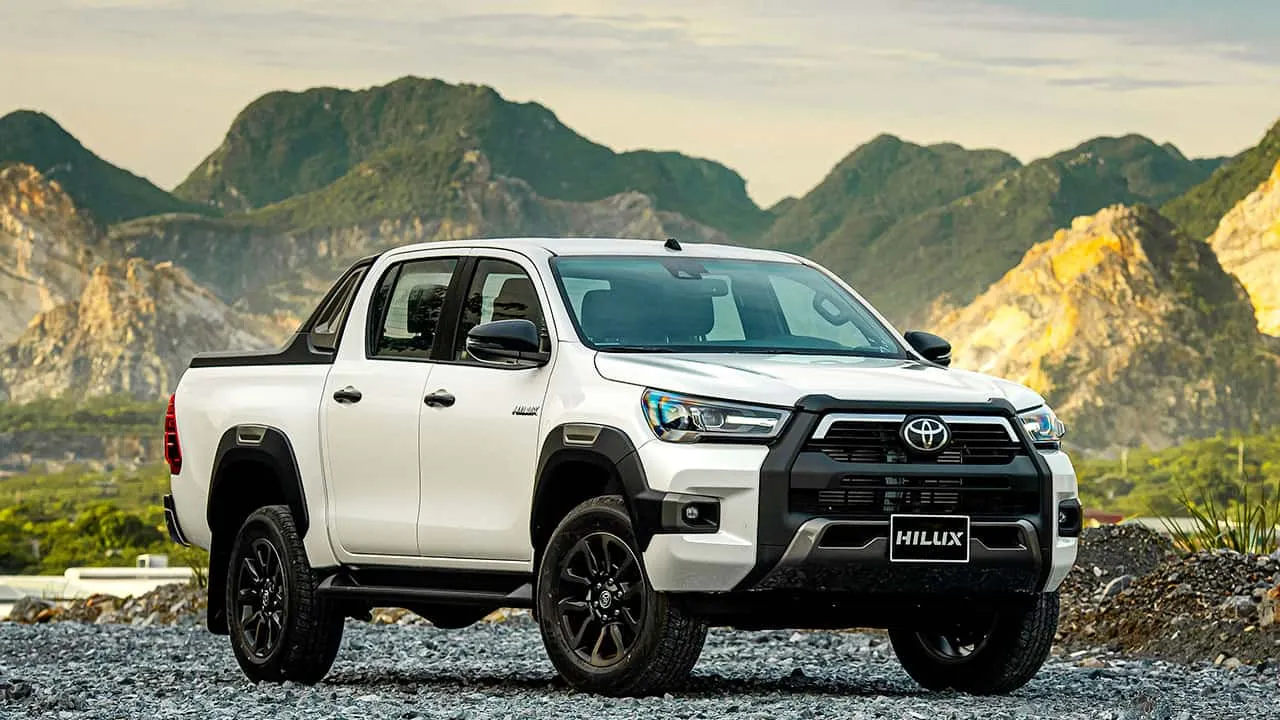 Xe bán tải Toyota Hilux màu trắng đậu trước nền trời xanh với thiết kế thân xe chắc chắn