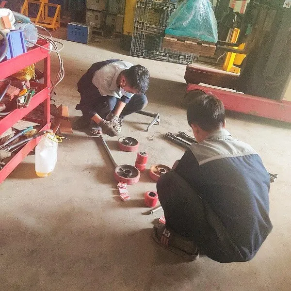 Kỹ thuật viên đang sửa chữa xe nâng tay tại kho hàng